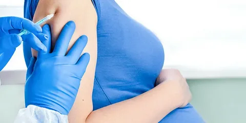 Pregnant woman receiving RSV vaccine injection from doctor during third trimester prenatal visit