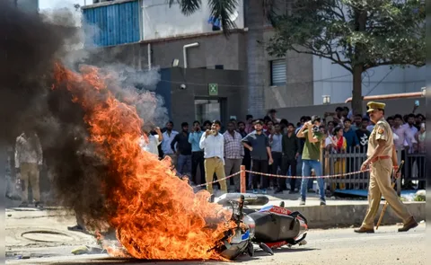 Workers protesting on the streets of Noida, India, demanding minimum wage hike in April 2026 with police in background