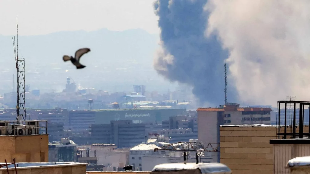 US Navy warships patrol the Strait of Hormuz during escalating US Iran war tensions, May 2026, with smoke rising from Iranian coastal targets