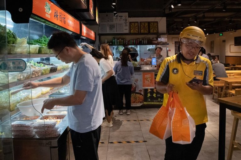 Busy urban street in China showing food delivery riders from Meituan and other apps navigating traffic during peak delivery hours.