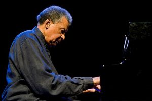 Portrait of Abdullah Ibrahim performing on piano, representing his legacy as a South African jazz icon and global music pioneer.