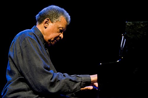 Portrait of Abdullah Ibrahim performing on piano, representing his legacy as a South African jazz icon and global music pioneer.