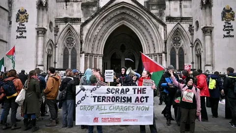 Protesters outside UK High Court during Palestine Action legal case hearing with banners supporting Palestine UK activism.