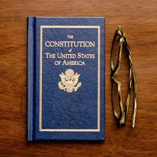 Printed U.S. Constitutional Law PDF with the Constitution of the United States and Bill of Rights displayed on a wooden desk