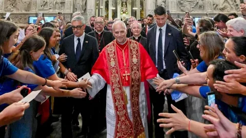 Pope Leo XIV standing beside Lampedusa migrants at the Gateway to Europe memorial on the Italian island