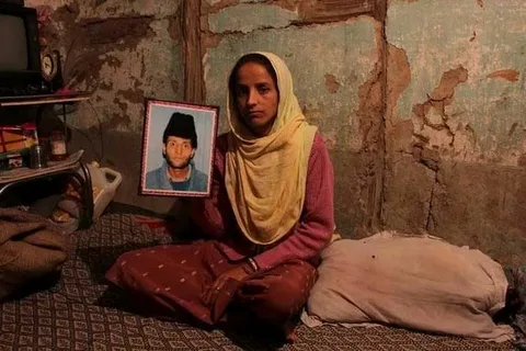 Family members of a disappeared Kashmiri man holding his photograph outside a Srinagar courtroom