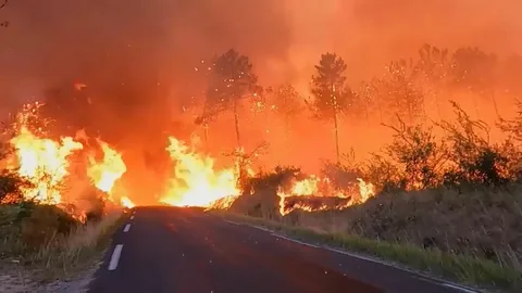 Wildfires burning across southern Europe during the record 2025 heatwave, showing flames and smoke rising over dry hillsides in Greece and Spain