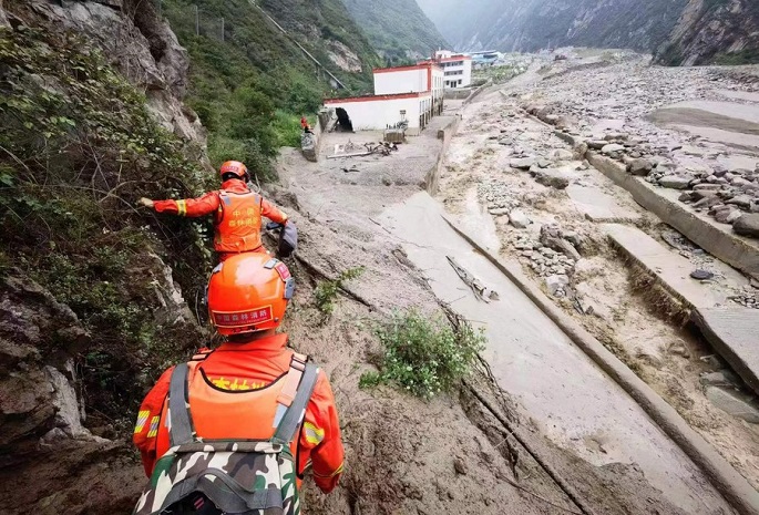 Rescue workers searching through landslide debris after heavy rainfall in China.