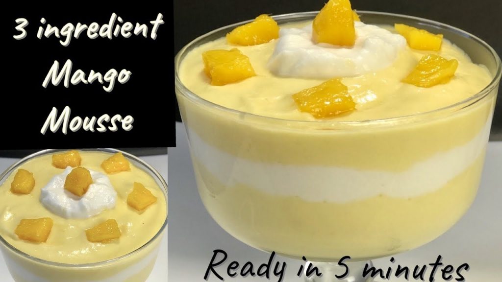 Creamy mango colada mousse served in a glass, topped with toasted coconut flakes and fresh mango slices