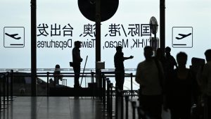 Chinese passport placed beside an airport departure board, symbolizing new China travel restrictions on citizens