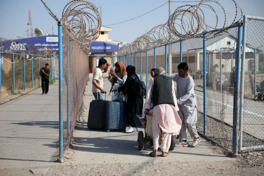 Afghan migrants carrying belongings cross the Islam Qala border from Iran into Afghanistan