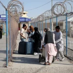 Afghan migrants carrying belongings cross the Islam Qala border from Iran into Afghanistan