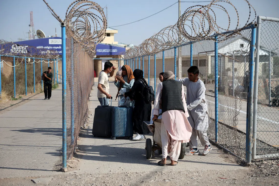 Afghan migrants carrying belongings cross the Islam Qala border from Iran into Afghanistan