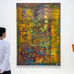 Young Gen Z art collectors viewing paintings at an Art Basel fair as a new UBS report shows record spending